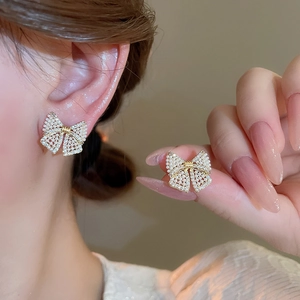 Close-up of pearl and rhinestone bow earrings showing exquisite craftsmanship and style