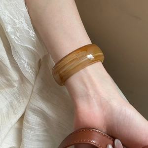 Close-up of model wearing an irregular amber resin bangle with marble texture finish