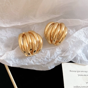 Detailed view of golden multi-layer spherical stud earrings with textured metallic finish