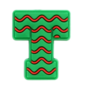 Macro view of green PVC letter T shoe charm with red wavy patterns for clog accessories