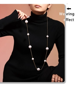 Long collier de perles dorées sur col roulé noir montrant un effet de port élégant