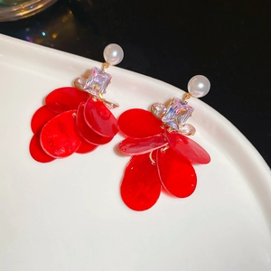 Detail of red petal earrings with white pearls and square crystals on a white plate
