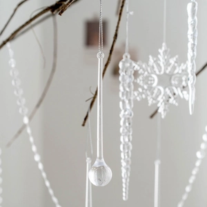 Transparent crystal icicle and snowflake Christmas tree ornaments on a winter branch