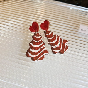 Detail of Christmas tree earrings with red glitter hearts and festive icing textures