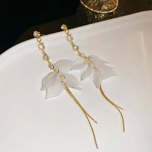 Détail de boucles d'oreilles à fleurs avec pétales en acrylique blanc et cristaux