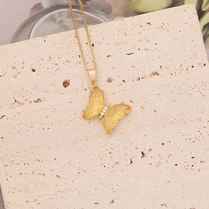 Détail du pendentif papillon avec ailes en résine jaune et zircon sur chaîne dorée
