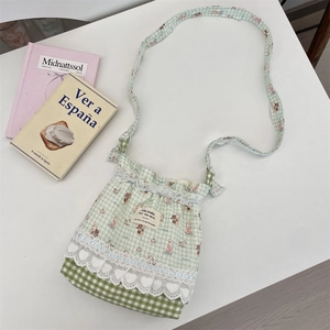 Detail of green gingham fabric bag featuring cute rabbit bear prints and white lace trim