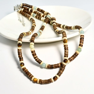 Close-up of coconut shell beads and tiger eye stone necklace on a ceramic tray