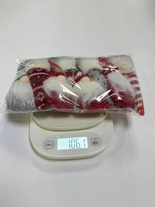 Set of 8 festive knitted Christmas gnomes showing lightweight plush material on a scale