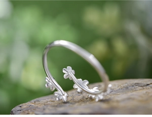 Macro shot of S925 sterling silver floral ring detailing small flowers on a rustic base