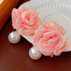 Elegant pink fabric flower earrings with large white pearls on a vintage ceramic plate