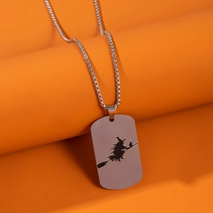 Macro detail of stainless steel dog tag necklace with a witch silhouette engraving