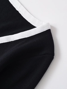 Detailed view of V-neck collar with contrast white trim and black knit fabric texture