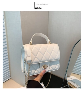 Detail of white quilted handbag featuring gold chain strap and elegant twist lock