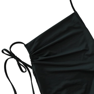Detailed close-up of back tie-up strings and ruched texture on a black bodycon dress
