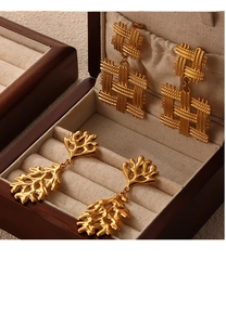 Detailed shot of vintage gold woven geometric earrings and organic leaf pendants on velvet