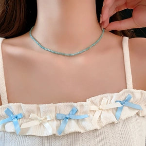 Gros plan d'un collier en perles de cristal bleu sur le cou d'une femme