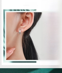 Detail shot of a 925 sterling silver leaf pattern hoop earring on a model ear