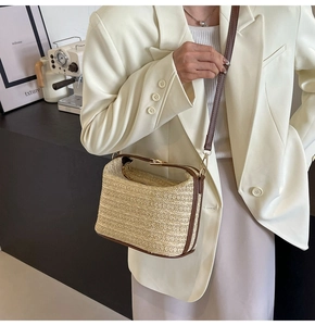 Dettaglio borsa a secchiello in paglia intrecciata con finiture in pelle marrone