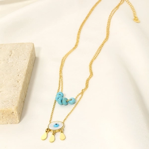 Detail einer goldenen Doppelkette mit blauem Evil Eye und Wassertropfen-Anhängern