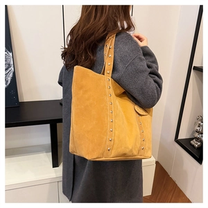 Detailed macro view of yellow-brown suede tote bag featuring silver rivet decorations