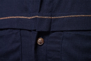 Detailed macro view of navy fabric with brown button and golden decorative stitching