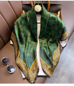 Foulard en soie vert avec motifs léopard et floraux drapé sur un haut blanc et un sac à main