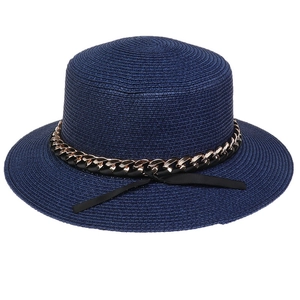 Detailed texture of dark blue woven straw sun hat with gold chain and black ribbon bow
