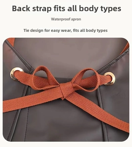 Detail view of the waterproof TPU apron showing orange cross-back straps and metal eyelets