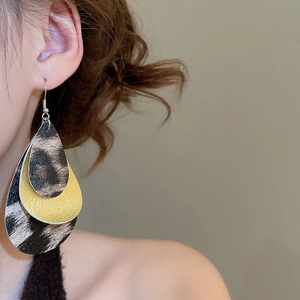 Detail of model wearing three-layer leopard print and yellow leather teardrop earrings
