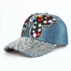 Détail de la casquette en denim avec papillon en strass et bordure effet usé