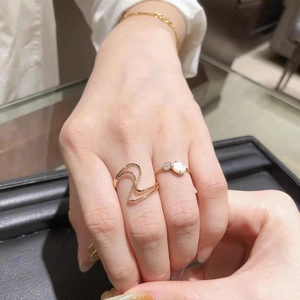 Minimalist 18K gold wave ring set with white round gemstone layered on fingers