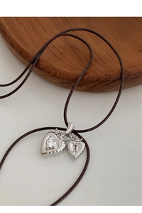 Detailed macro view of double heart pendant with diamond texture and dark cord necklace
