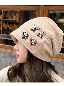 Detailed view of four panda sports badges on a beige knit hat worn by a model