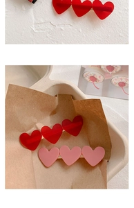 Close-up of heart-shaped acrylic hair clips in red and pink on a decorative tray