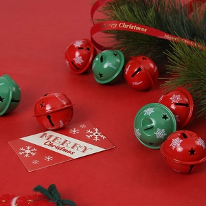 Red and green Christmas tree bells with snowflake patterns and star cutouts on pine branch