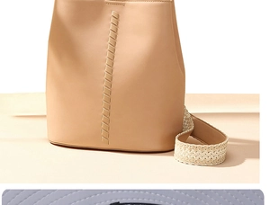 Gros plan sur la large bandoulière tissée texturée d'un sac seau en cuir beige