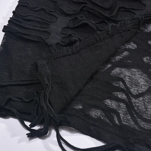 Detail of black hollow-out knitted fabric with distressed texture and long tie straps