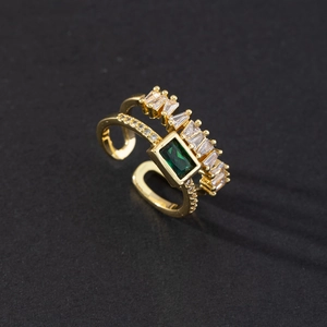 Macro detail of emerald-cut green stone and zircon inlay on a gold double-layer open ring