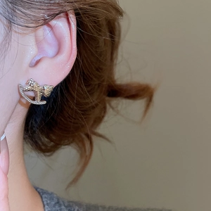Vue détaillée d'une boucle d'oreille poney sertie de zircons avec une texture de métal martelé