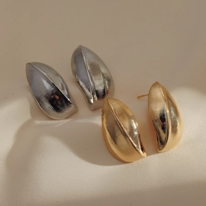 Minimalist leaf-shaped geometric earrings in gold and silver finish on beige fabric