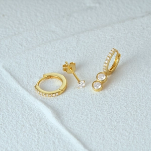Detail of three-piece gold earring set with micro-pave crystals on white mineral stone