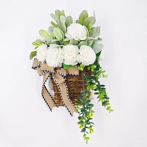 Detail of white peonies and eucalyptus in woven vine basket with burlap bow decor