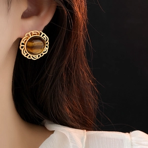 Detailed view of vintage gold hollow-out stud earrings with round tiger eye stones on model