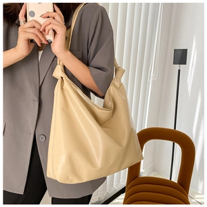 Detail of a large cream tote bag showing the unique shoulder strap knot design and PU leather
