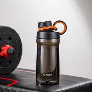 Sleek smoke gray sports water bottle on gym equipment with stylish black and orange cap