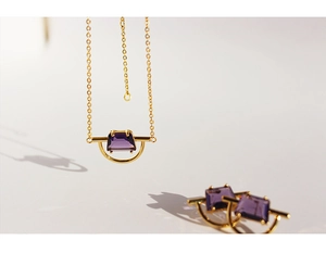 Macro detail of gold-plated necklace and earrings set with purple zircon stones