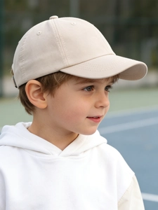 Close-up of a child wearing a beige minimalist cotton baseball cap in an outdoor setting
