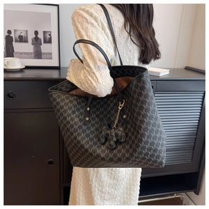 Detalle de bolso tote gris oscuro con estampado M y un lindo colgante de elefante