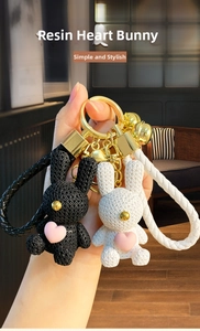 Handheld view of creative resin bunny keychains with pink hearts and braided lanyards